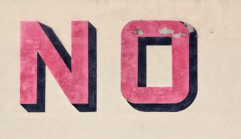 Beige wall with the word "NO" painted in large red letters.